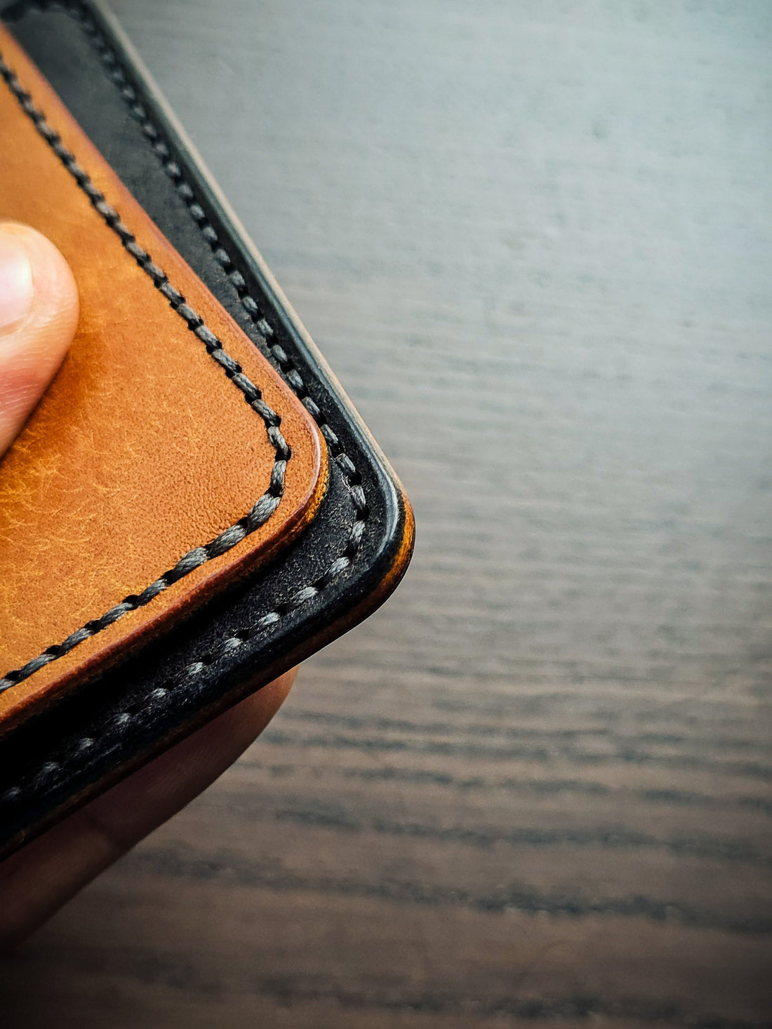 Detail photograph of a leather wallet corner highlighting stitch placement, edge distance, reinforcement, and structural design decisions.