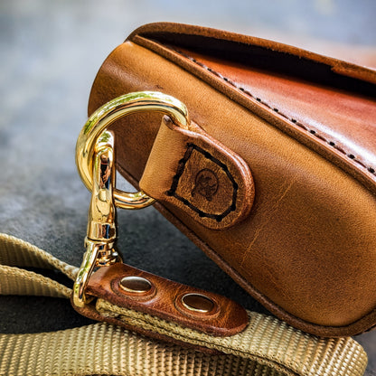 Detailed view of the Renee crossbody bag showing brass hardware, reinforced leather attachment points, and handcrafted construction.