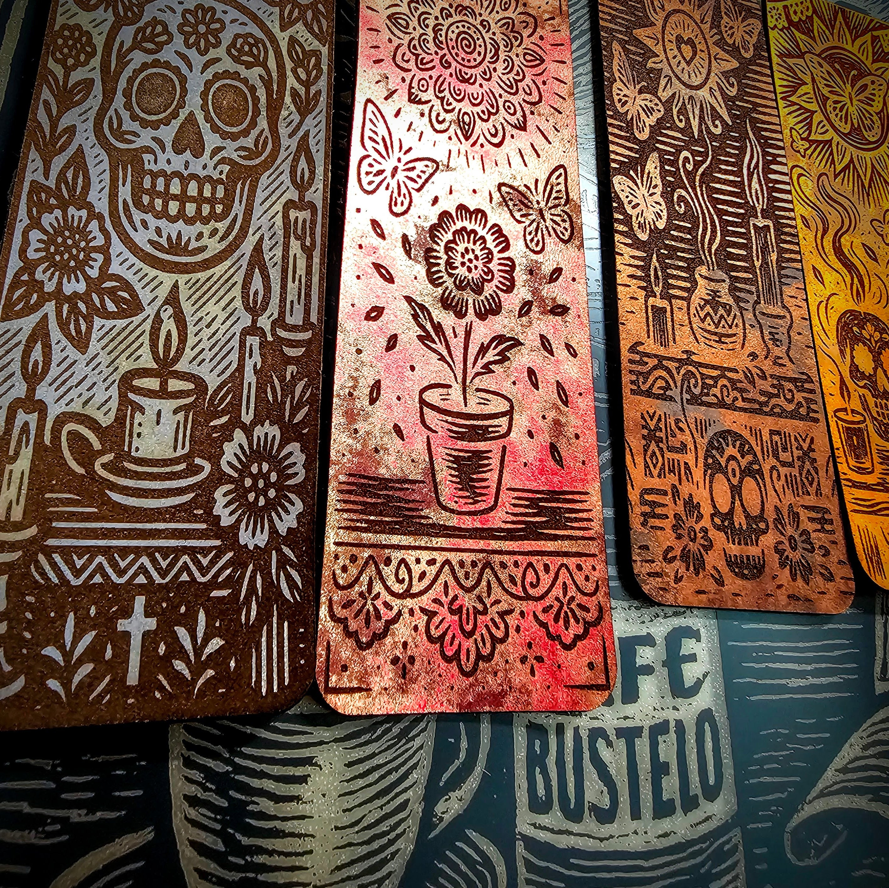 Metallic leather bookmarks displayed on an engraved glass mirror, representing the studio's exploration of craft, memory, culture, storytelling, and material transformation.