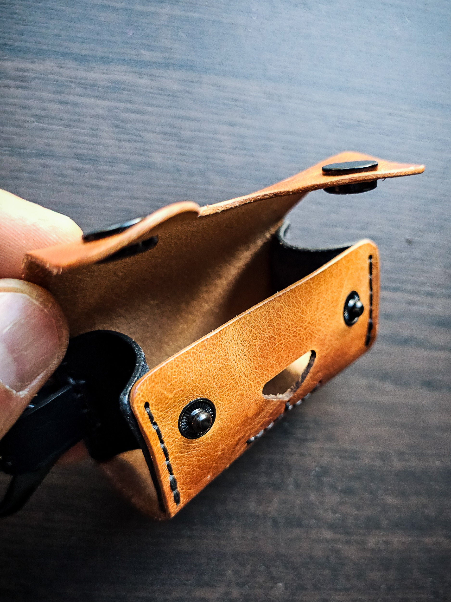 Side view of the Doggy Duty leather waste bag dispenser showing folded construction, snap closure, and attachment hardware.