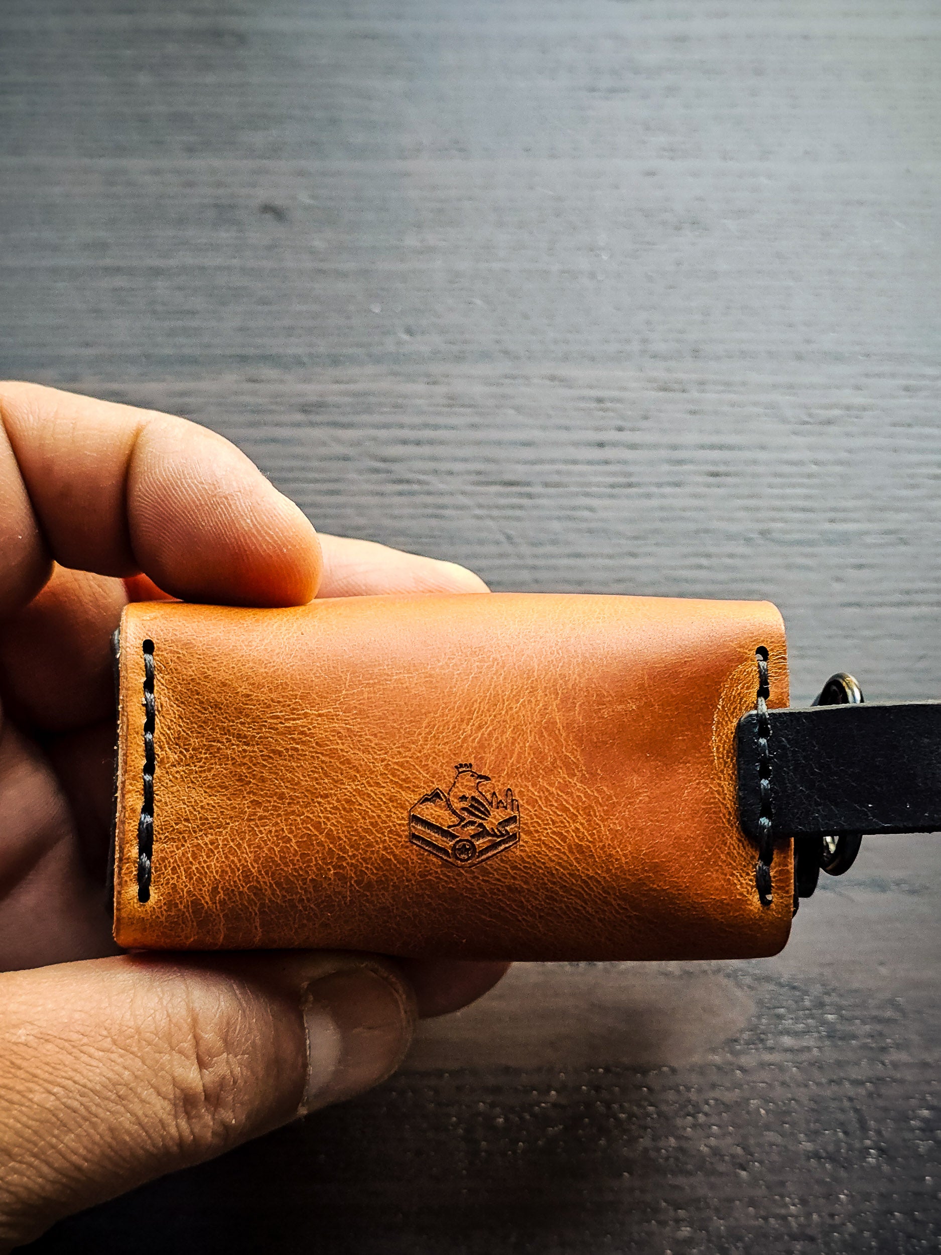 Hand holding the Doggy Duty leather waste bag dispenser to demonstrate size, portability, and handcrafted construction.