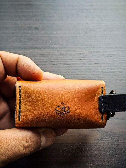 Hand holding the Doggy Duty leather waste bag dispenser to demonstrate size, portability, and handcrafted construction.