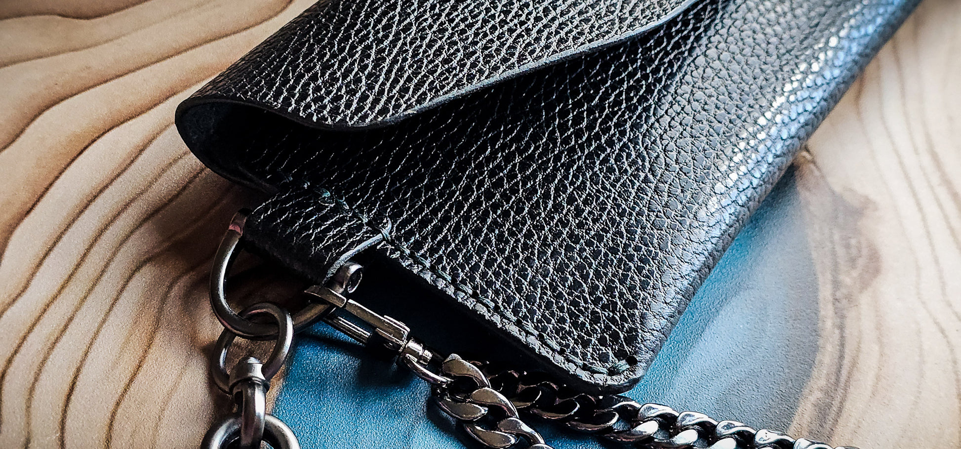 Close-up detail of the Delilah Clutch showing pebbled leather texture, edge finishing, and chain attachment.