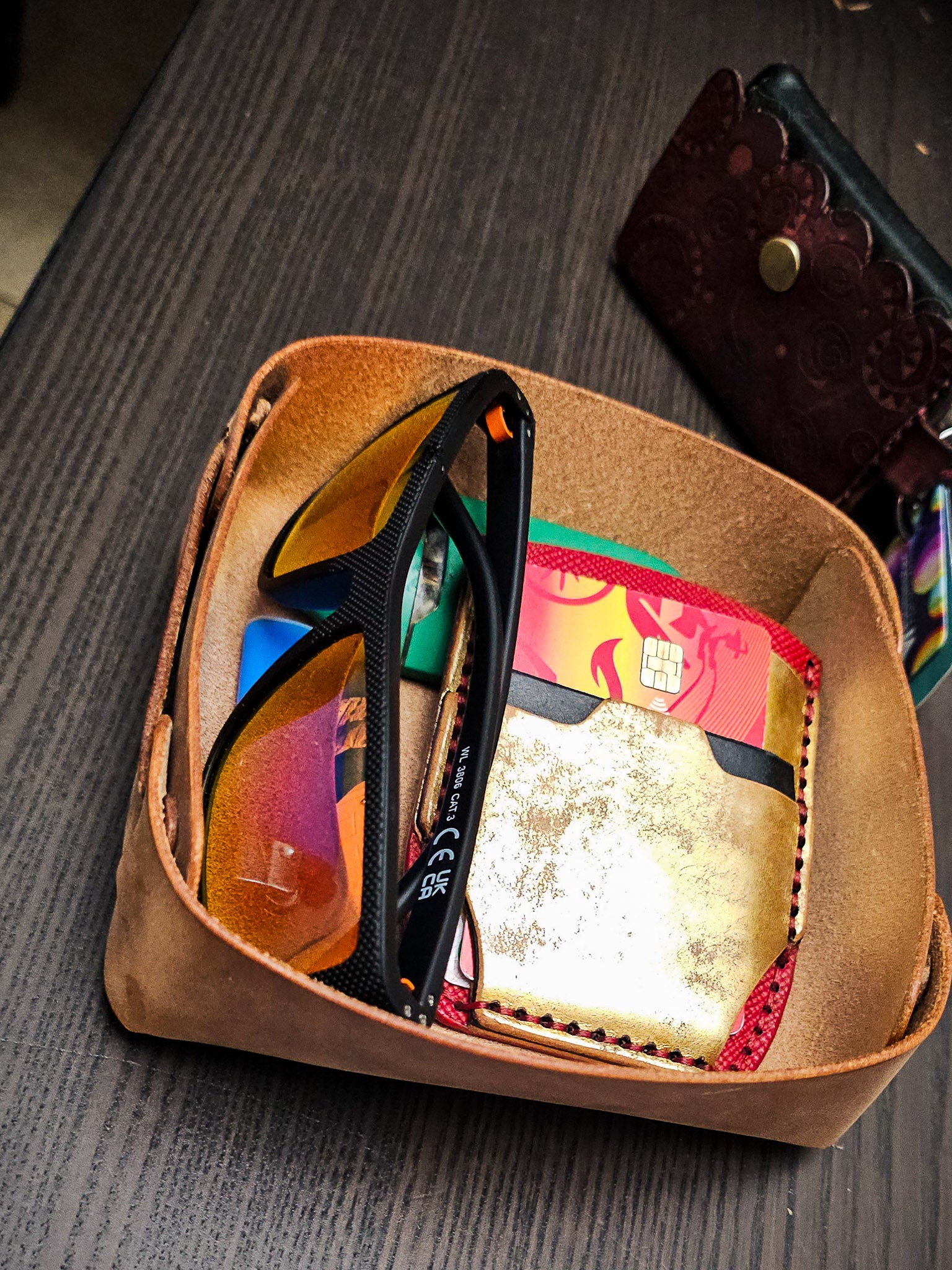 The Nest leather valet tray holding everyday carry items including sunglasses, notebook, wallet, pen, and accessories in a compact catchall design.